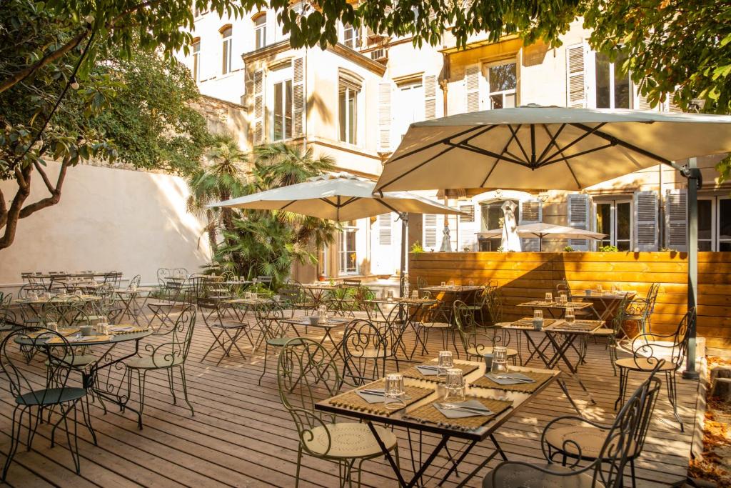 马赛老港穆葛杭之家酒店的一个带桌椅和遮阳伞的户外庭院。