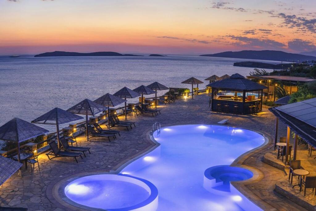 巴特斯欧Blue Bay Resort Village的日落时分带游泳池和海洋的度假胜地