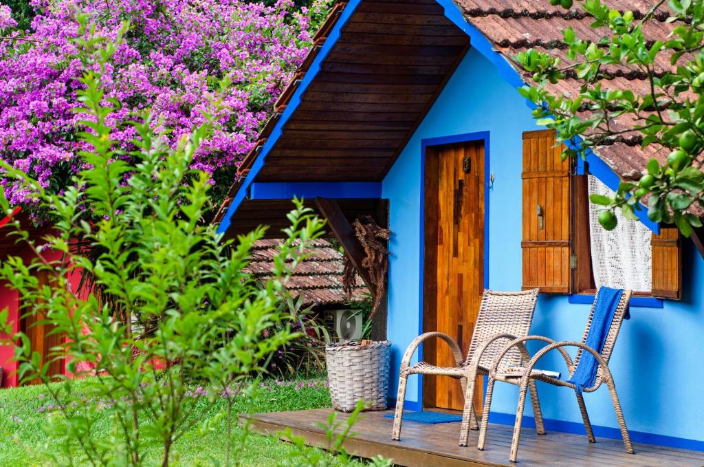 维奥康德马奥Pousada Colher de Chá的蓝色房子,带两把椅子和鲜花