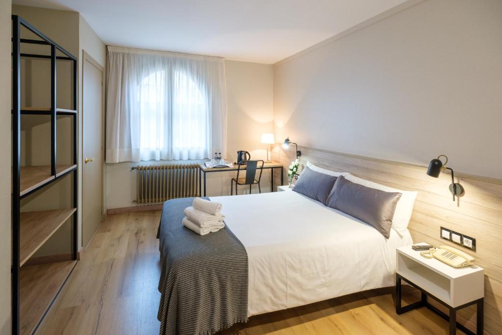 曼列乌Hotel Torres Manlleu的卧室配有一张白色大床和一张书桌