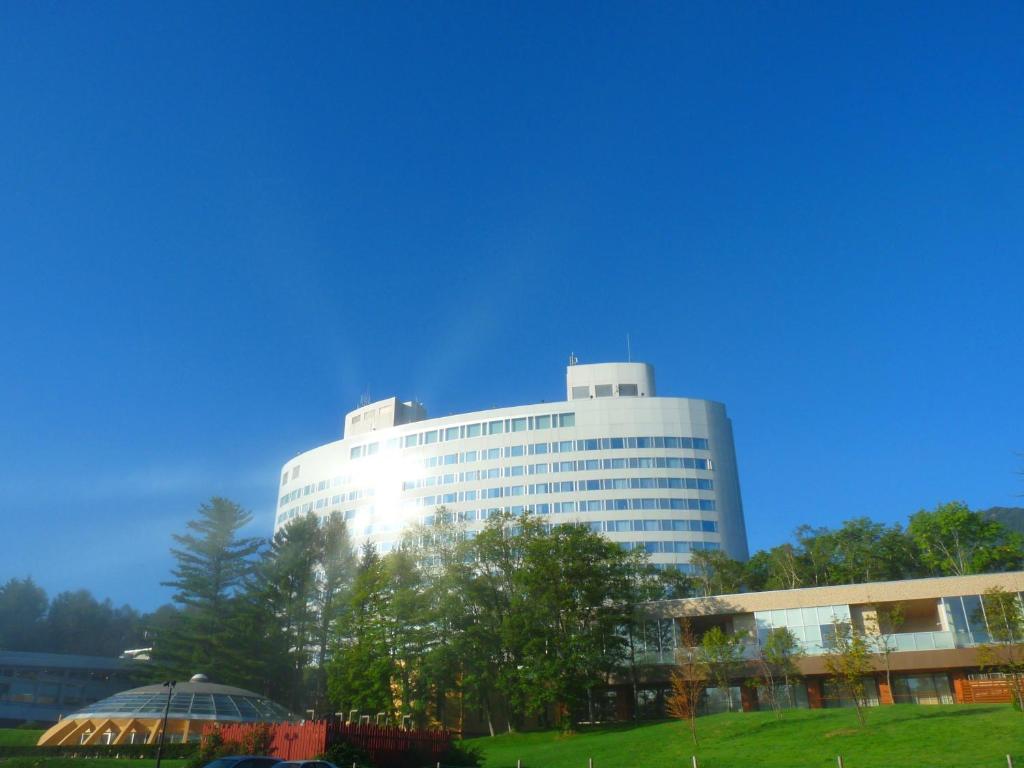 富良野Shin Furano Prince Hotel的前面有树木的白色大建筑