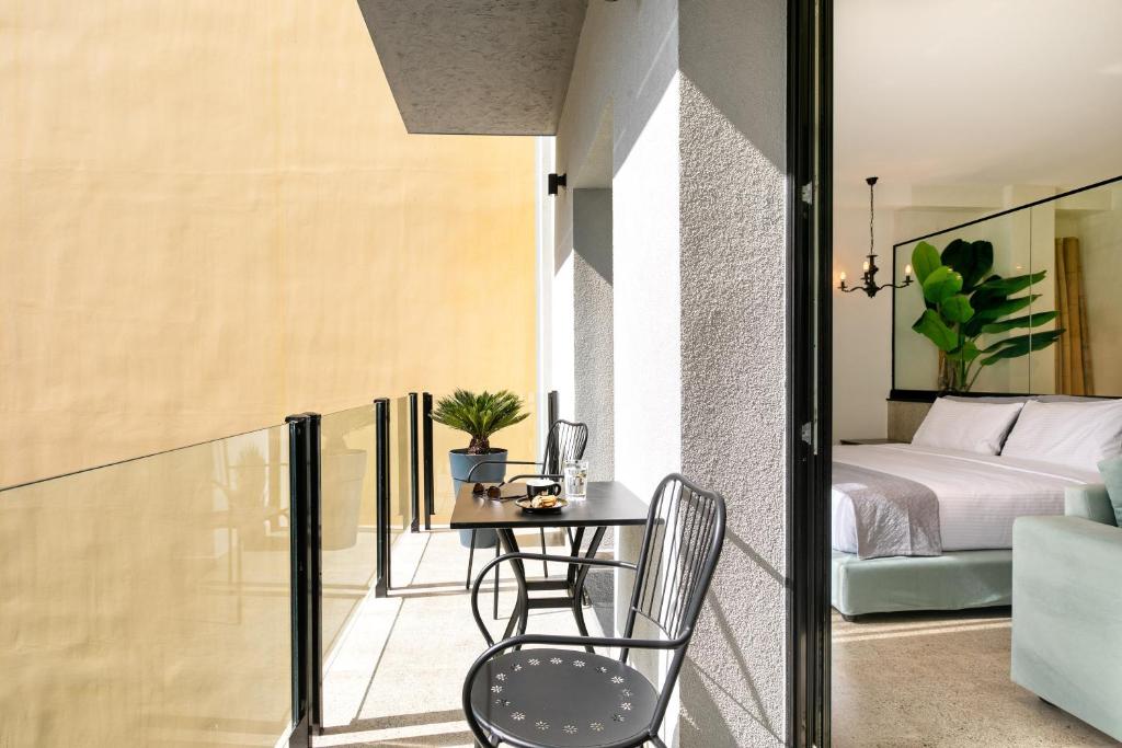 雅典Athens Ivy Suites的客房设有带桌子和床的阳台。