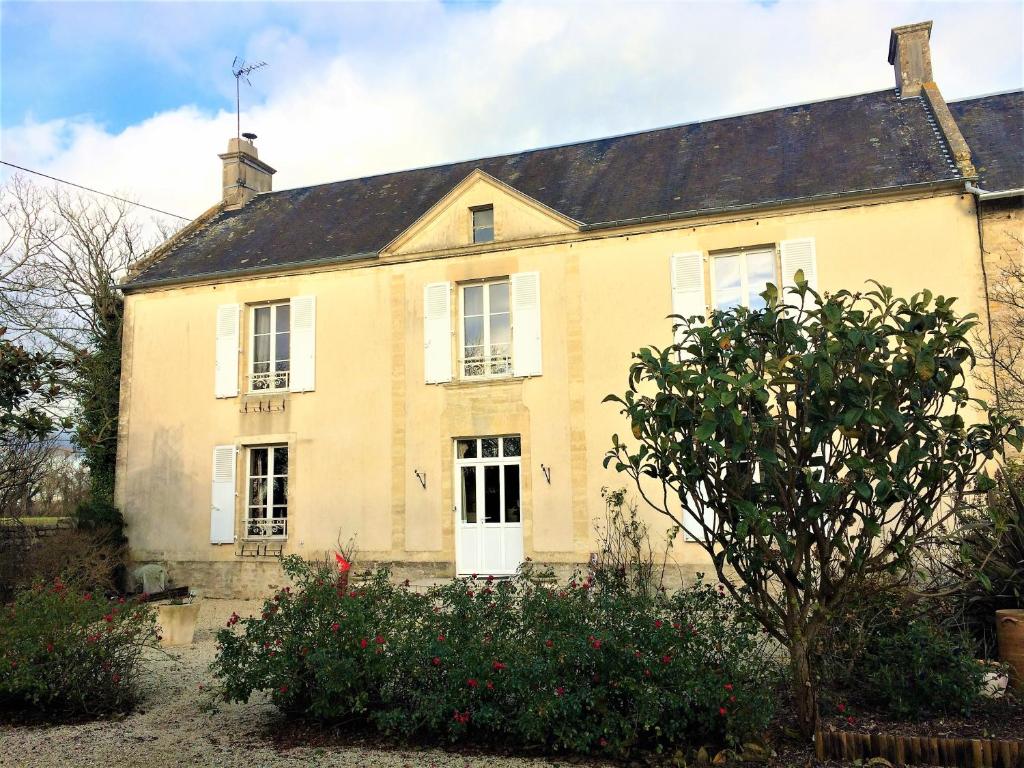 滨海维耶维尔Les chambres d'Omaha Beach Etablissement avec deux chambres d'hôtes, petit-déjeuner compris fait-maison et produits locaux的一座带屋顶的大型黄色房屋