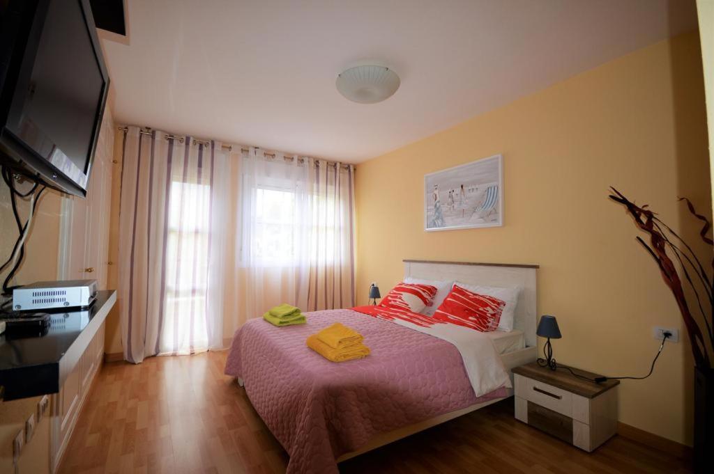 阿德耶Villa Elena , Costa Adeje的一间卧室配有一张带红色枕头的床和电视。