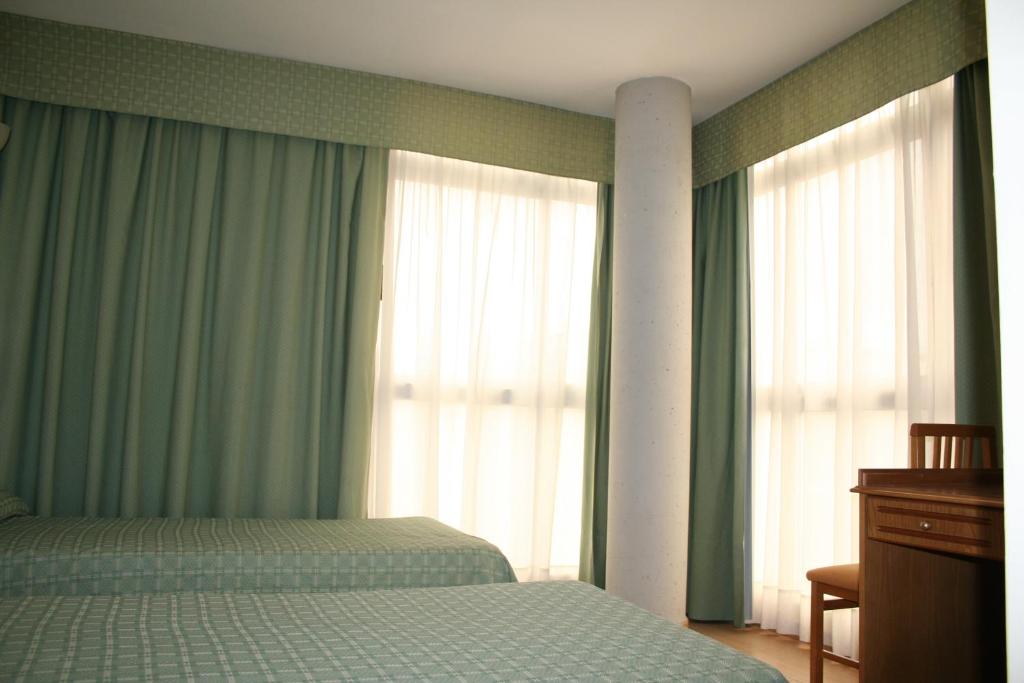 波多黎多德萨贡托奥地利76号酒店的一间卧室设有床和配有绿色窗帘的窗户