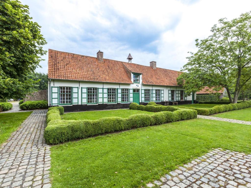 贝尔内姆Beautiful farmhouse in Beernem with big garden的一座带红色屋顶和绿色庭院的古老房子