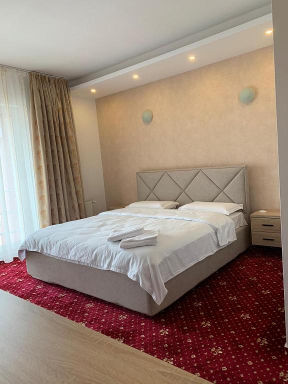 VeştemHotel Veștem的一间卧室配有一张大床,铺有红地毯