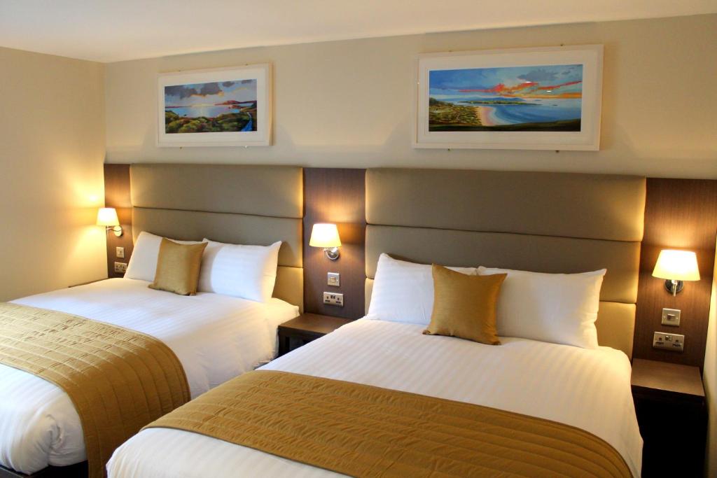 康多纳Joyce's Carndonagh Inishowen的酒店客房,设有两张床和两张墙上的照片