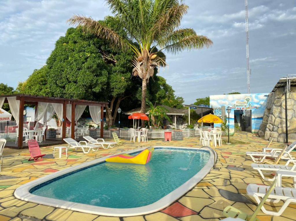 博阿维斯塔Pousada Country K的一个带桌椅的游泳池,以及棕榈树