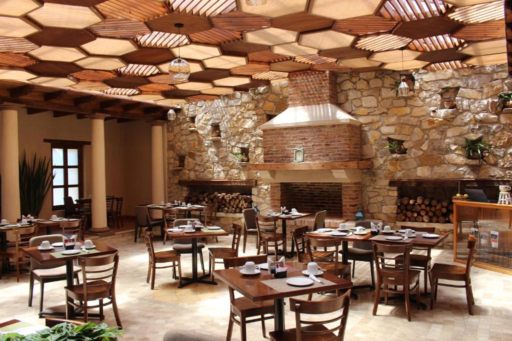 圣克里斯托瓦尔-德拉斯卡萨斯La Estancia的一间设有木桌和椅子的餐厅以及石墙