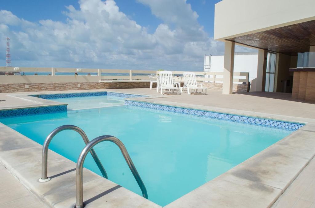 马塞约Aram Ouro Branco Hotel的一个带椅子和海滩的大型游泳池