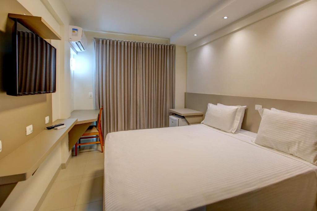 戈亚尼亚Novares Hotel的配有一张床和一张书桌的酒店客房