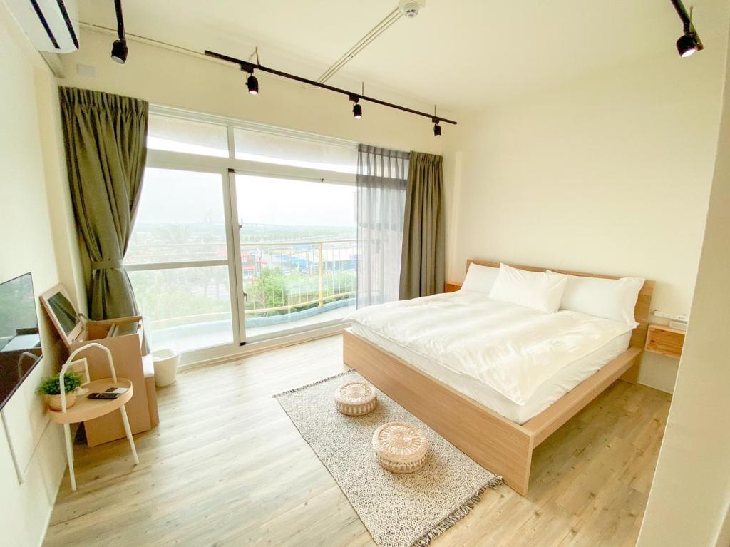 东港艾睏khùn行旅的一间卧室设有一张大床和一个大窗户