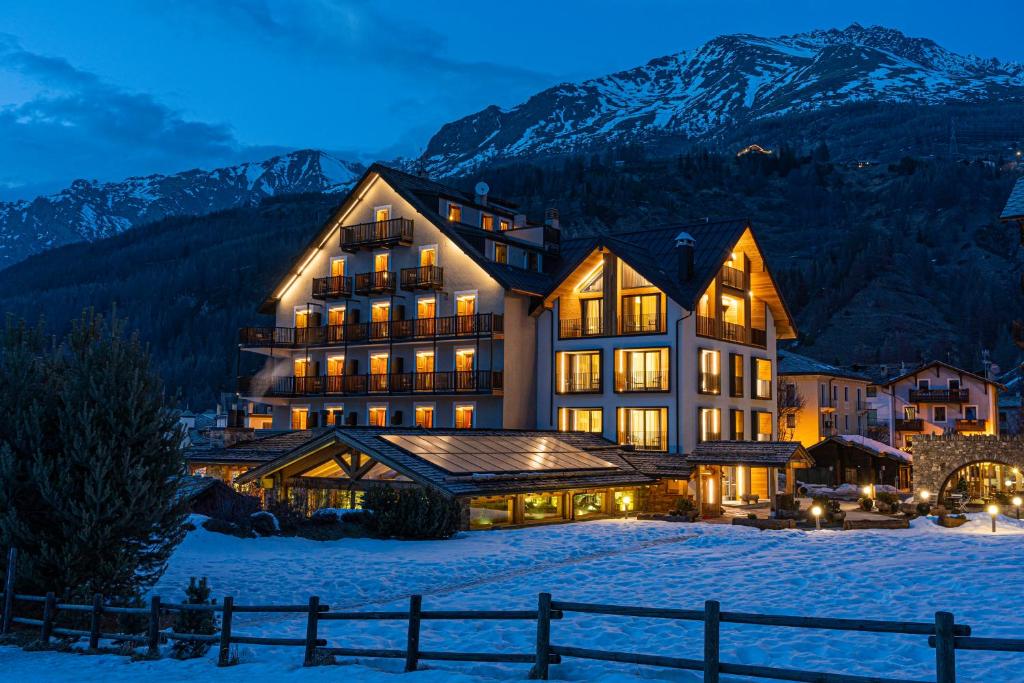 科涅Hotel Sant'Orso - Mountain Lodge & Spa的一座大建筑物,在晚上下雪