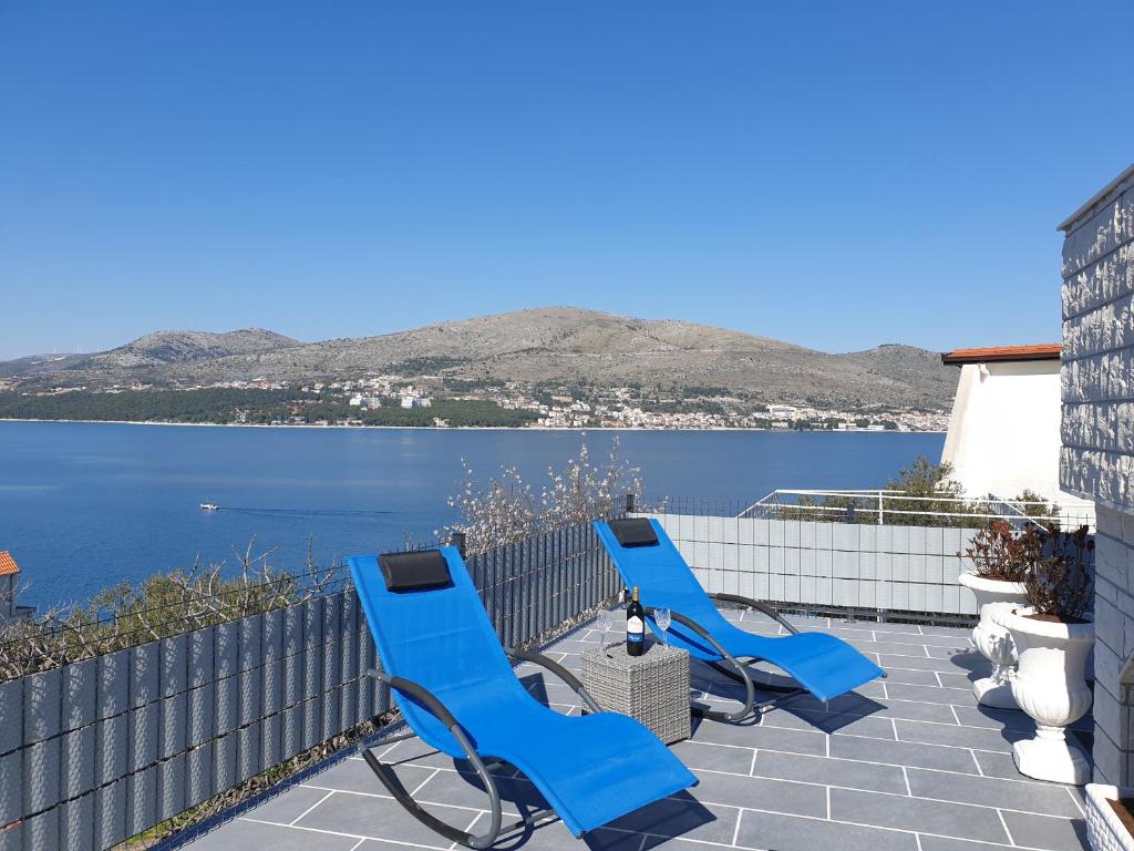 奥库格哥恩基Villa Sandrina的三个蓝色椅子坐在俯瞰着水面的露台上