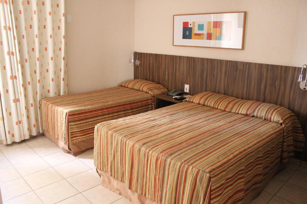 普雷图河畔圣若泽利维埃拉酒店的酒店客房设有两张床,墙上挂着一张照片。