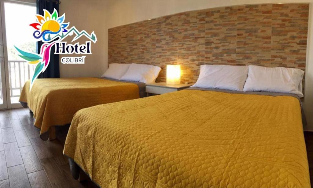 克雷尔HOTEL COLIBRÍ的酒店客房设有两张床,墙上有标志
