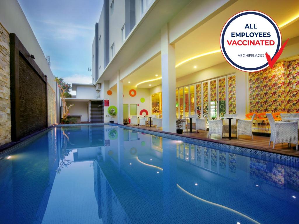 日惹库苏曼尼卡拉大街酒店的一座酒店游泳池,上面有标志,上面写着所有员工都应该