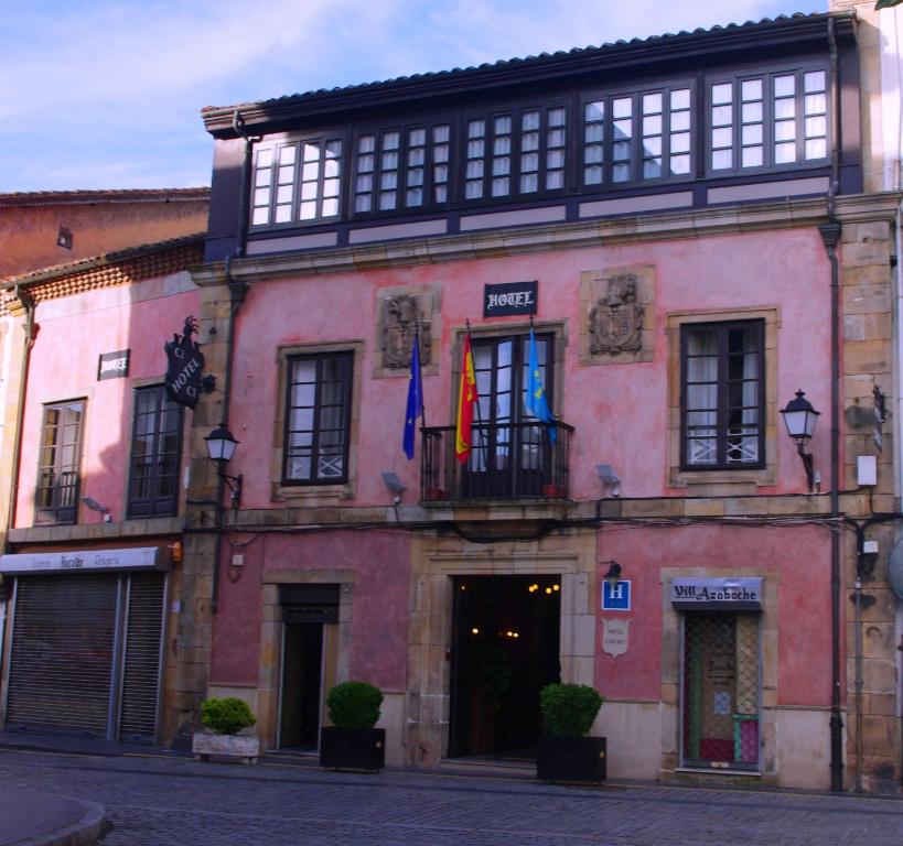 比利亚维西奥萨Hotel Palacio Carlos I的粉红色的建筑,前面有旗帜