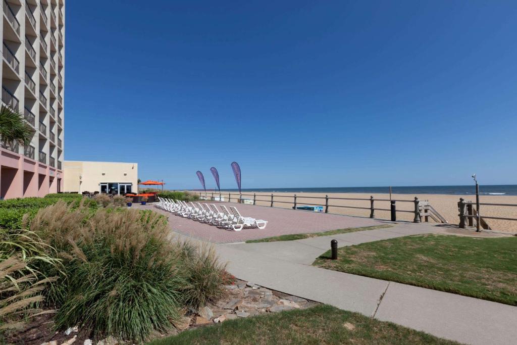 弗吉尼亚海滩温德姆弗吉尼亚海滩海滨酒店的一个带躺椅的海滩、一座建筑和大海