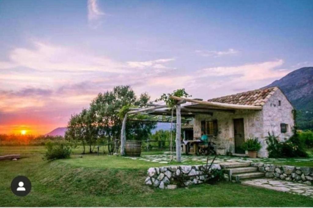 格鲁达Vineyard Eco Cottage near Dubrovnik的地里的小房子,背面是日落
