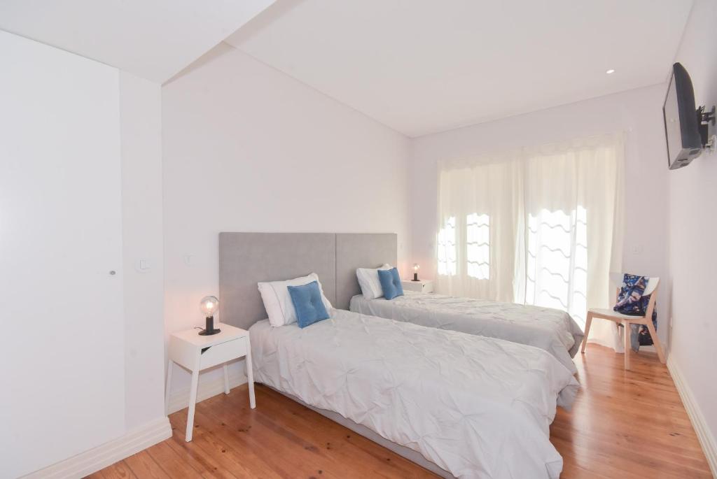阿威罗Peixinho Avenue Apartment的一间白色卧室,配有两张床和电视