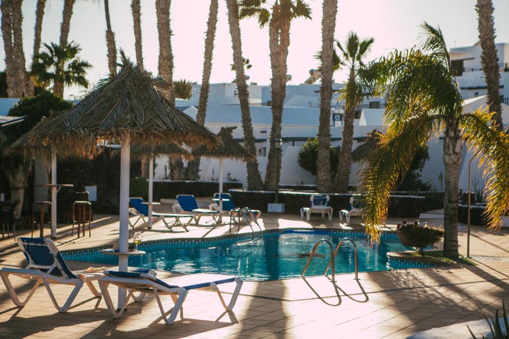 卡门港蓝色海洋海滩公寓式酒店的一个带椅子的游泳池,棕榈树