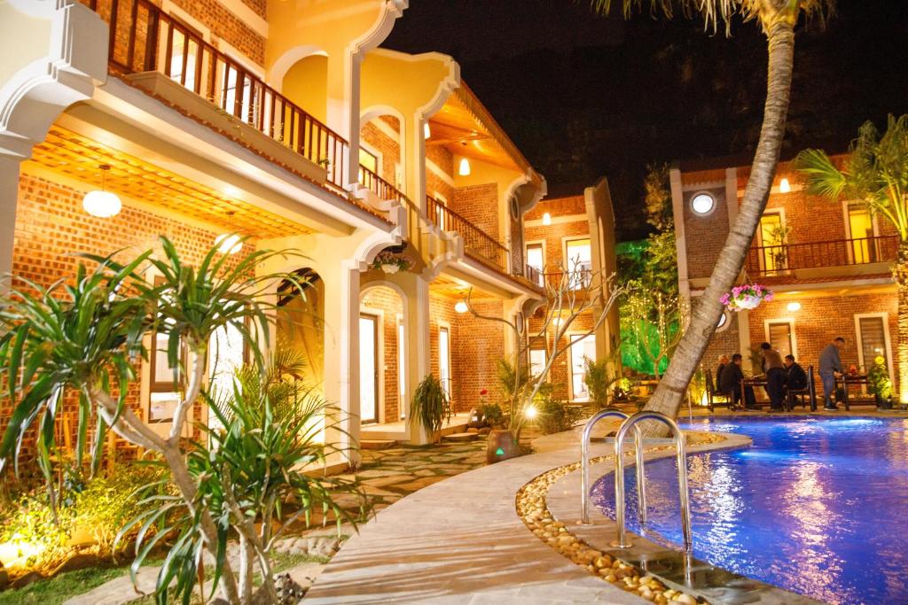宁平Trang An Aroma Homestay的一座晚上设有游泳池的房子