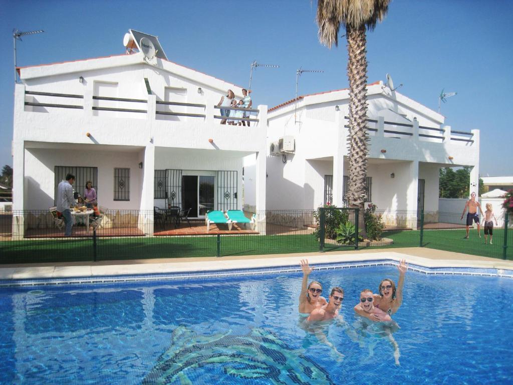 科尼尔-德拉弗龙特拉Apartamentos Los Olivos的三个女人在房子前面的游泳池里