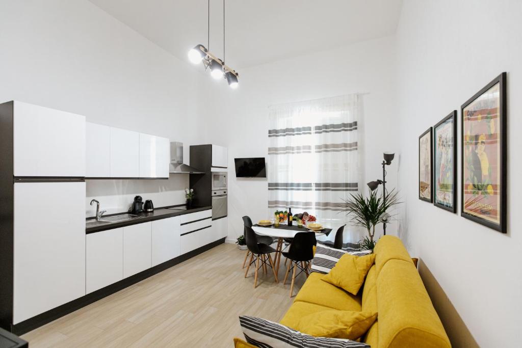 锡拉库扎Les Amis的一间带黄色沙发的客厅和一间厨房