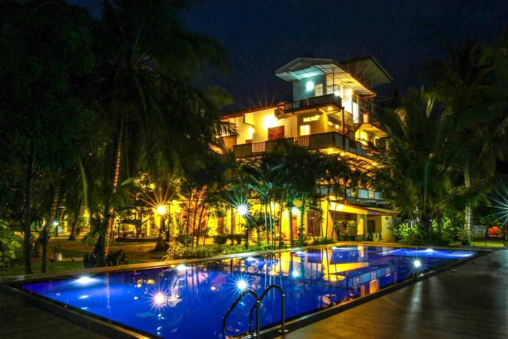 蒂瑟默哈拉默Hotel Nilketha Yala Tissamaharama的一家在晚上设有大型游泳池的酒店