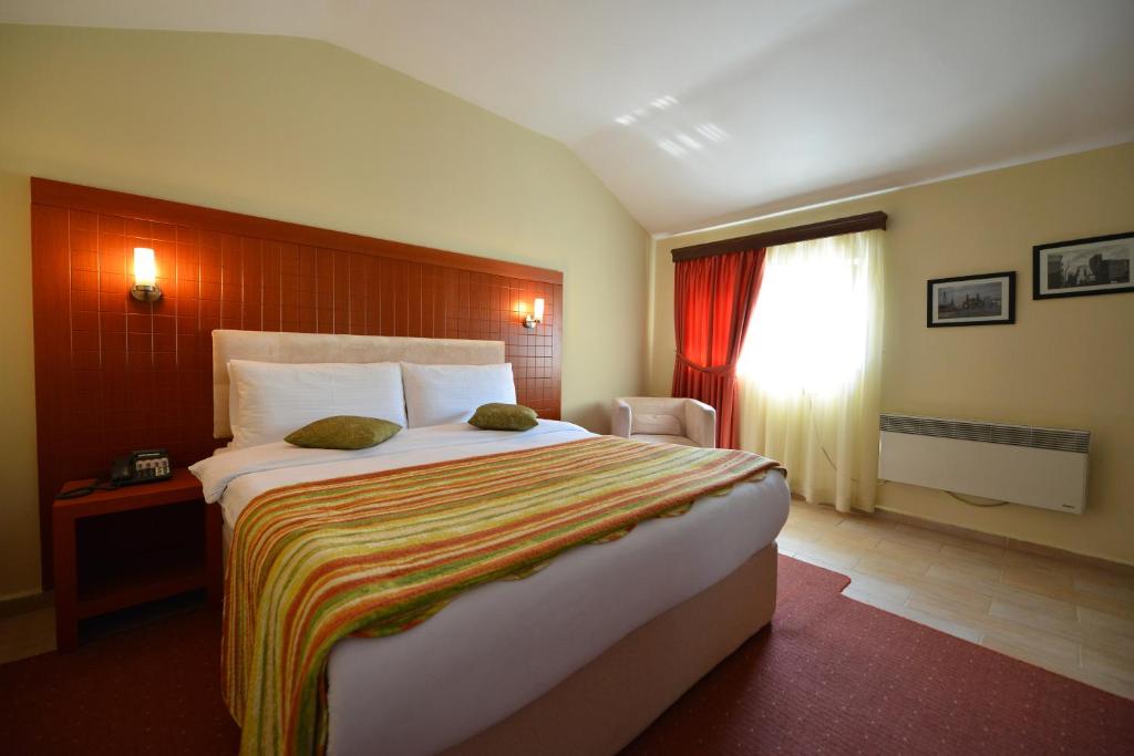 地拉那City Hotel的一间卧室设有一张大床和一个窗户。