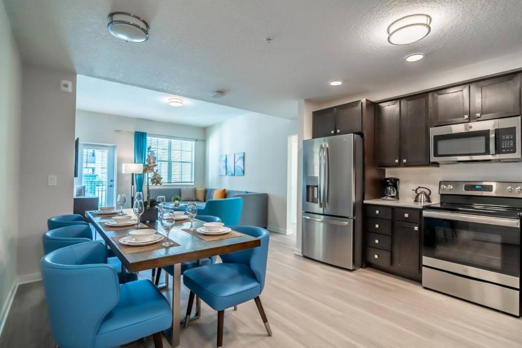 奥兰多4013 Vista Cay 2的厨房以及带桌子和蓝色椅子的用餐室。