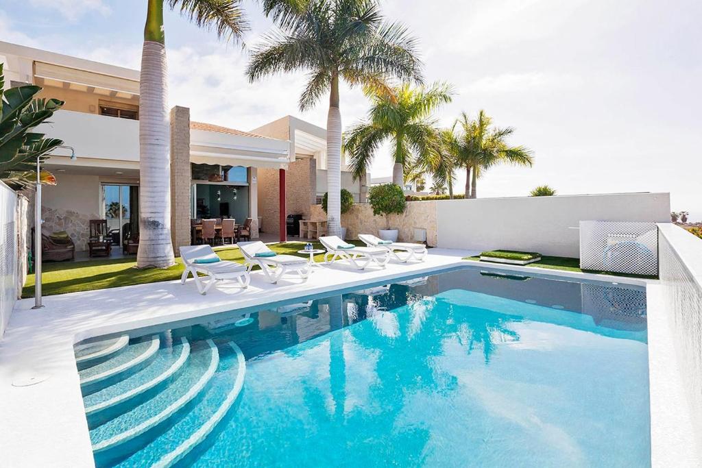 阿德耶Villa La Caleta Golf的一个带椅子的游泳池以及一座房子