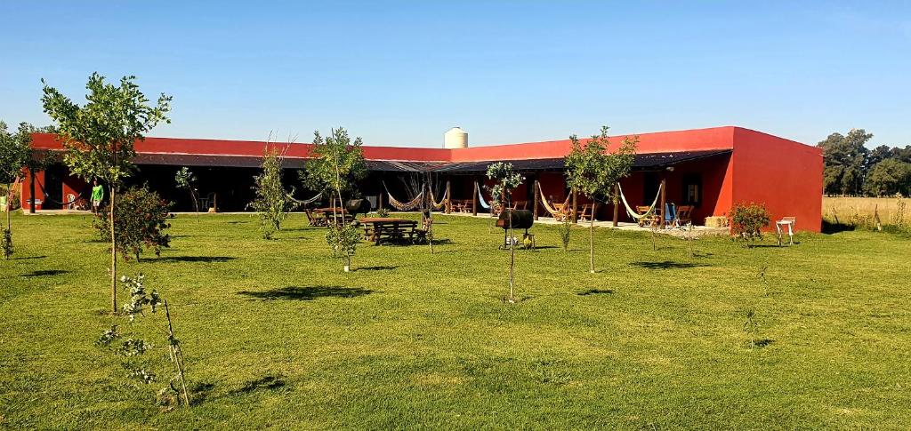 乌里韦拉雷亚La Maína Uribe Posada的一座红色的建筑,在田野里种着桌子和树木