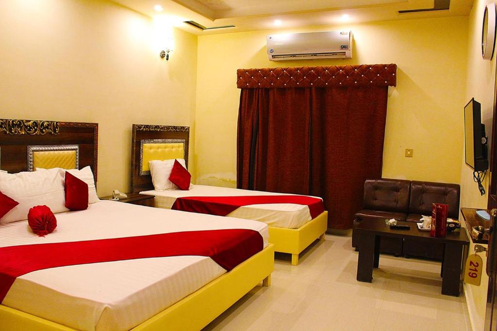 拉合尔Hotel Day In Lahore的酒店客房设有两张床和窗户。