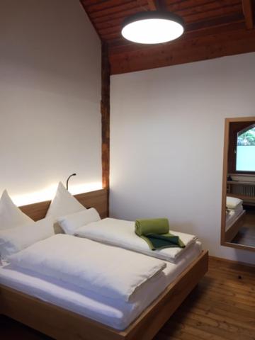 于伯林根Naturata Hotel的一间卧室配有一张带白色床单和镜子的床