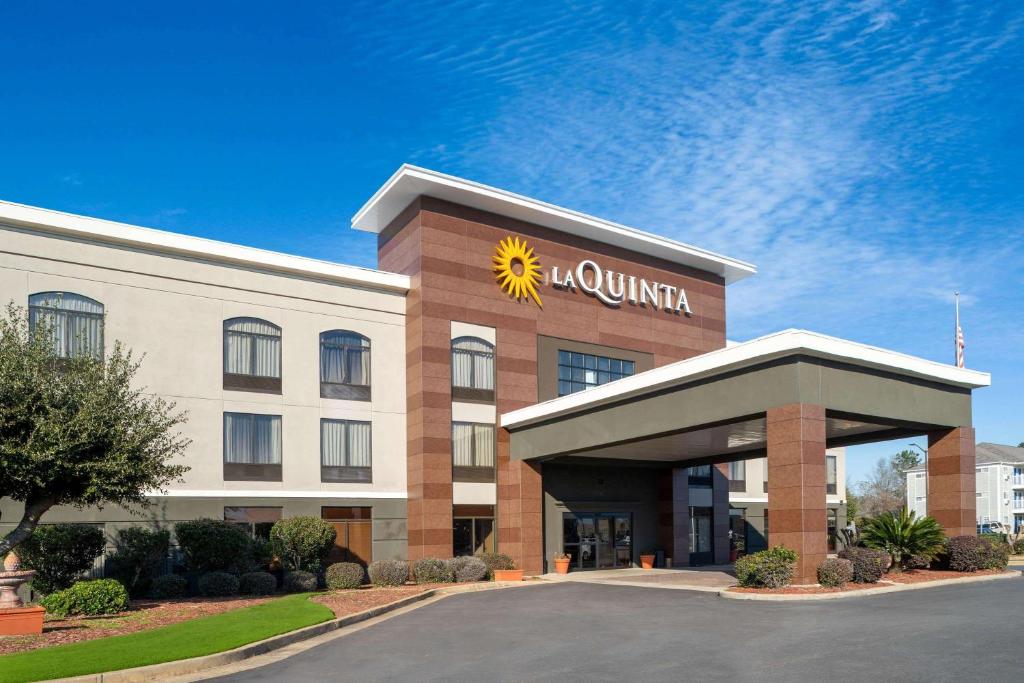 奥尔巴尼La Quinta Inn & Suites by Wyndham-Albany GA的建筑前方有太阳标志的酒店