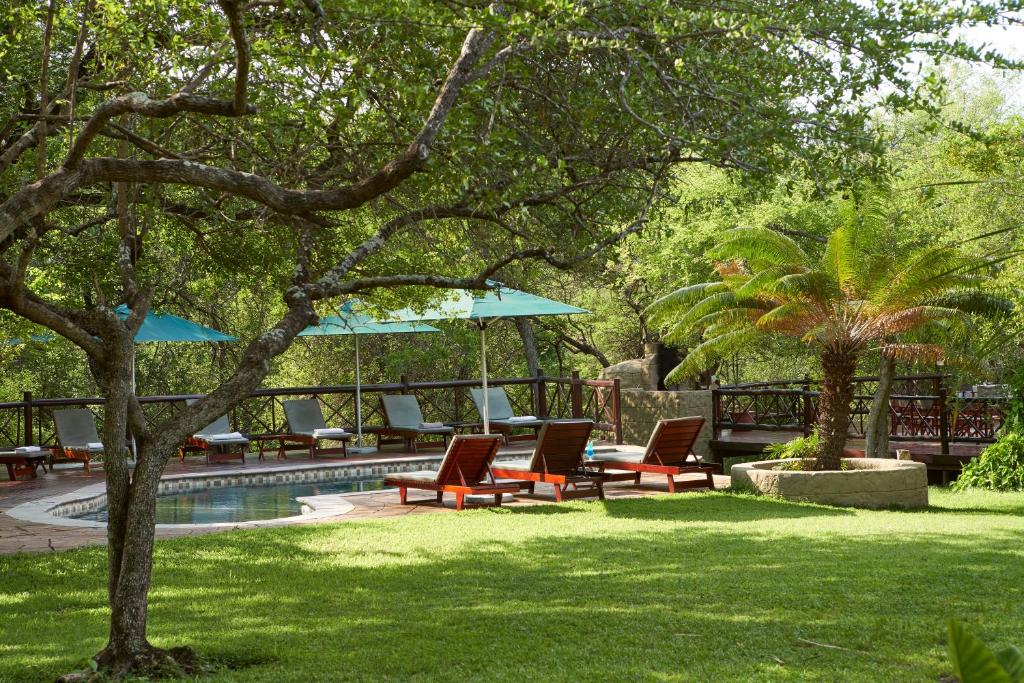 玛洛斯帕克格兰德克鲁格Spa旅馆的游泳池旁带椅子和遮阳伞的庭院