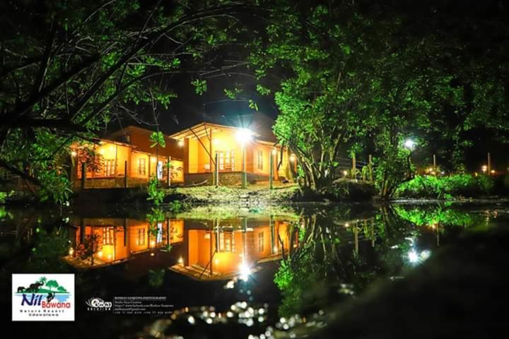 达瓦拉维Nil Bawana Nature Resort的水中反射的夜晚房屋
