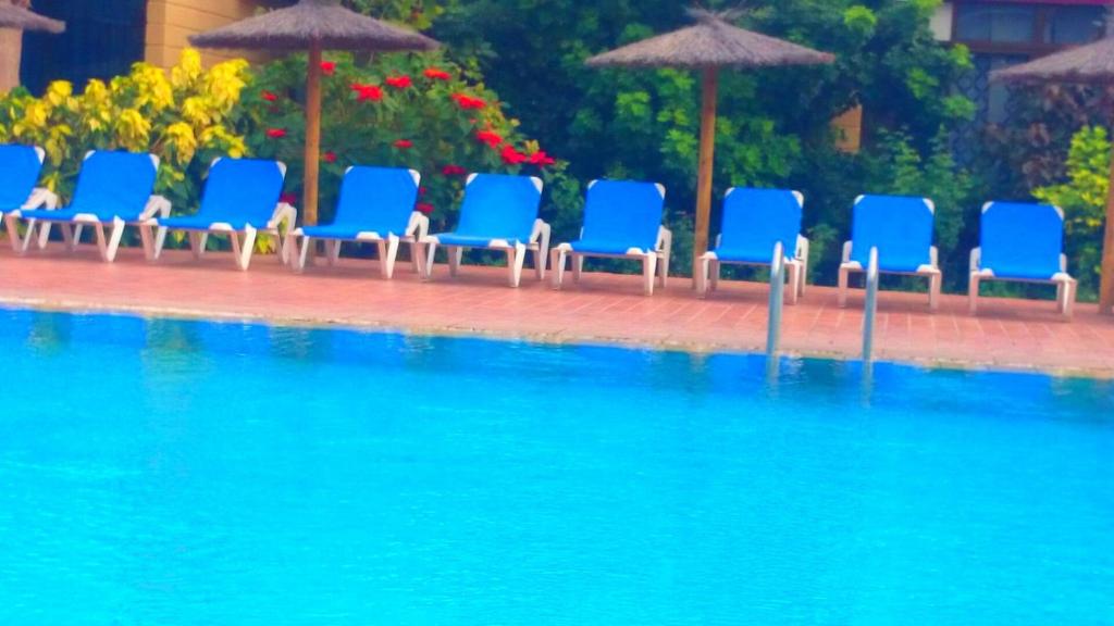 德尔锡伦西奥海岸大力士公寓的一组蓝色椅子和遮阳伞,位于游泳池旁