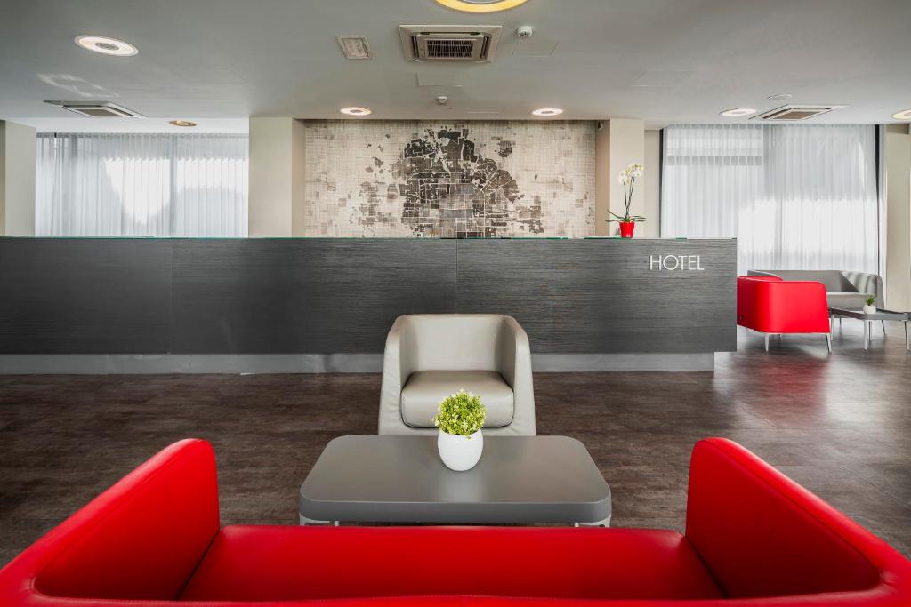塞格拉泰Fasthotel Linate的一间设有红色椅子和桌子的等候室