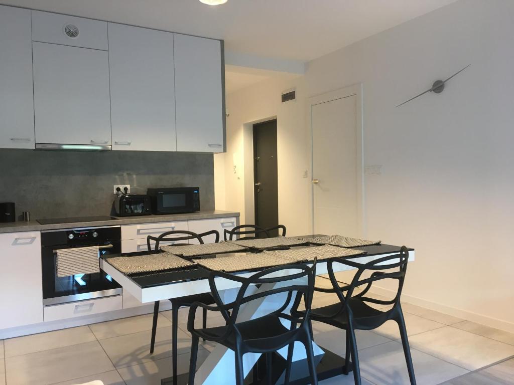 雷布尼克Apartament Fibra Grande的厨房配有白色橱柜和桌椅