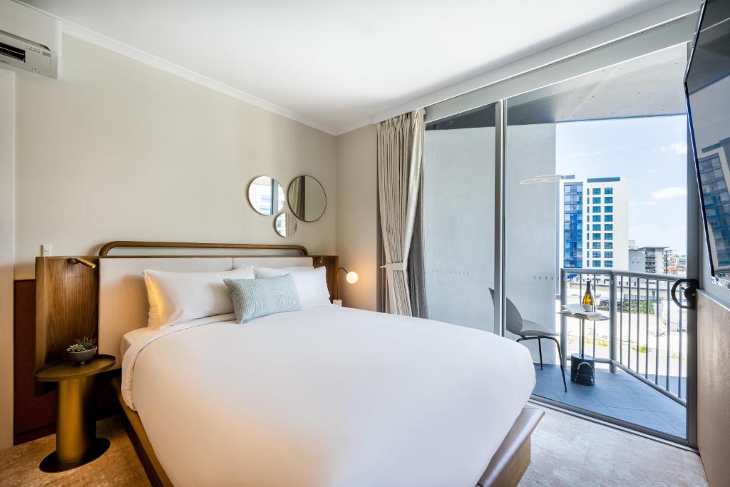 布里斯班曼特拉特勒斯酒店的一间带白色床的卧室和一个阳台