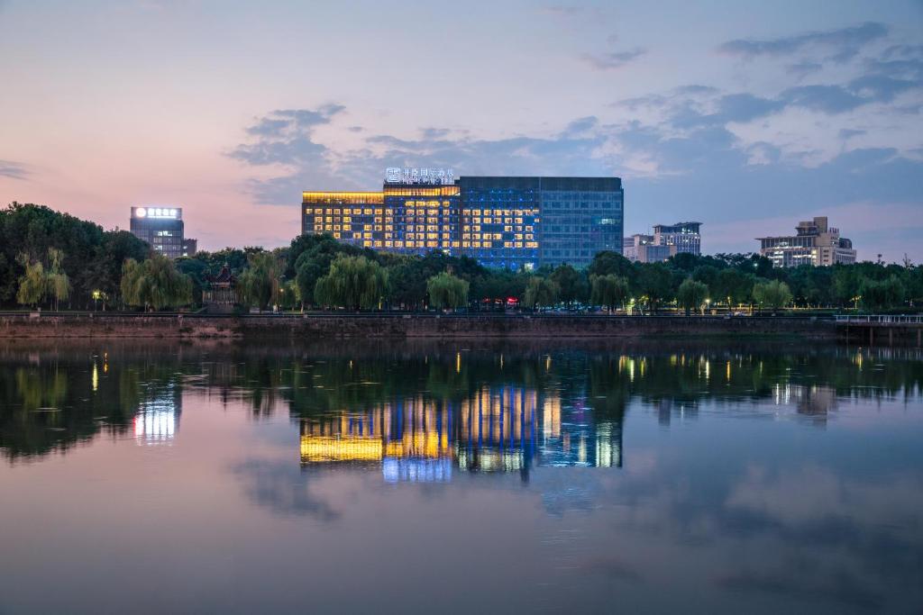 义乌义乌开臣国际酒店的城市天际线,水面上有一栋楼