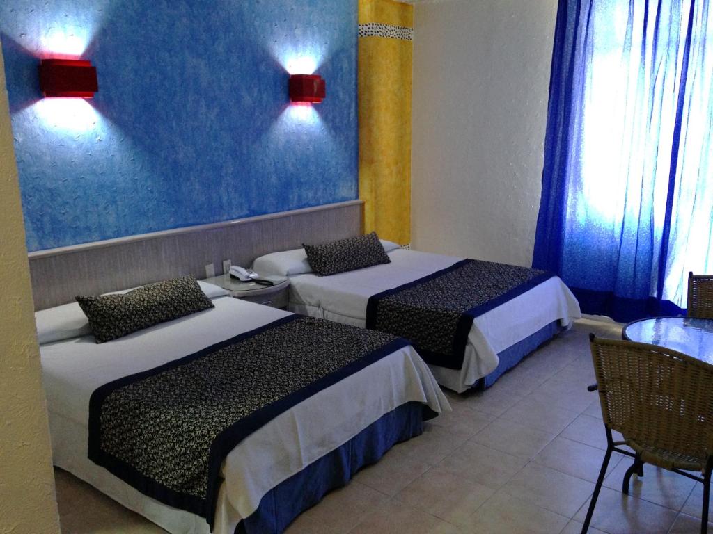 阿卡普尔科Hotel Club del Sol Acapulco by NG Hoteles的酒店客房设有两张床和一张桌子。