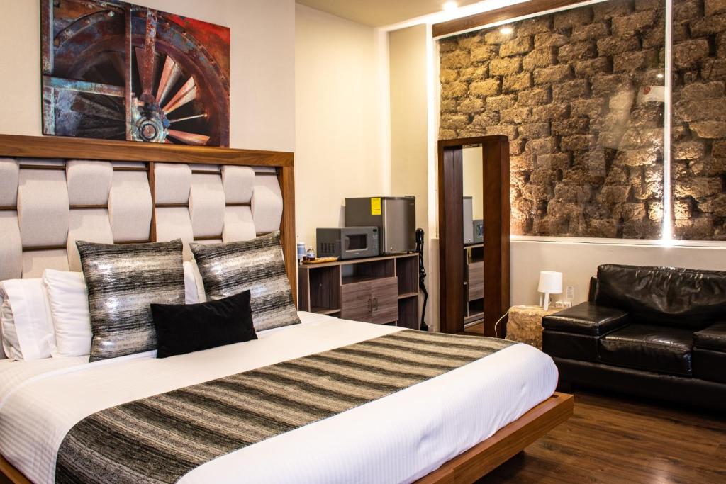 蒙特雷Hoteles ANTIGUA - SANTA LUCIA MTY的一间卧室配有一张大床和一张黑色皮椅