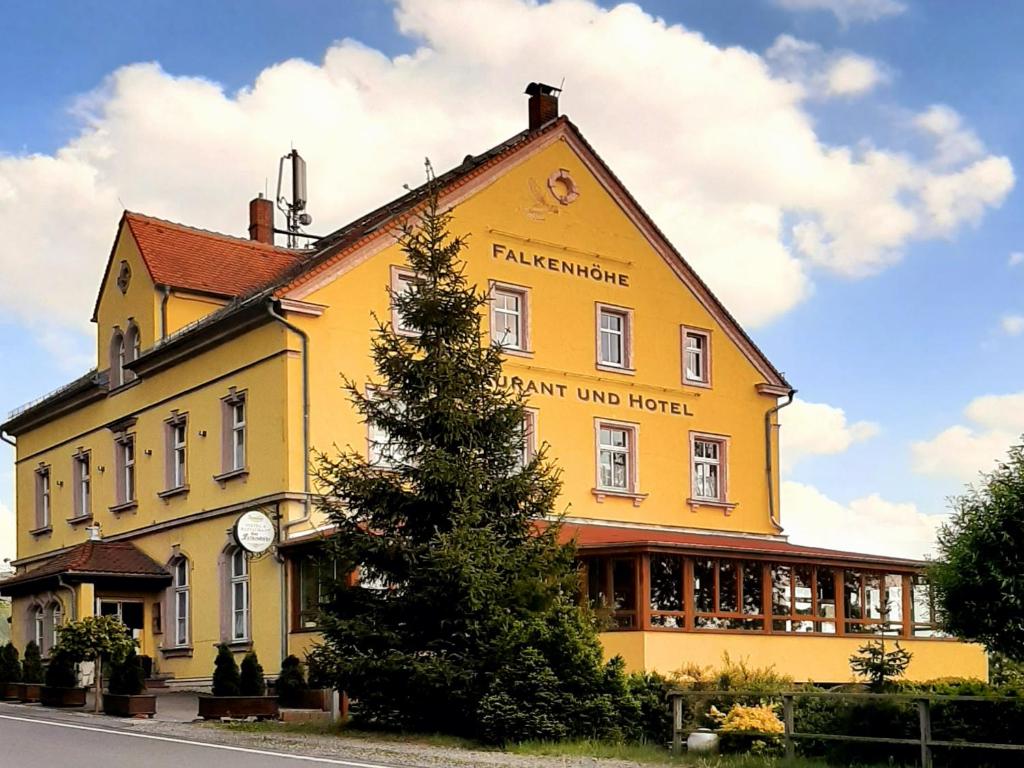 FalkenauRestaurant & Hotel Zur Falkenhöhe的黄色的建筑,旁边是钟