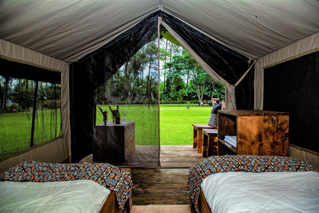 姆托瓦姆布Africa Safari Camping Mto wa Mbu的帐篷配有两张床,还有一人坐在长凳上
