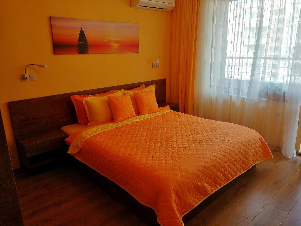 布尔加斯Sunny的一间卧室配有带橙色床单的床和窗户。